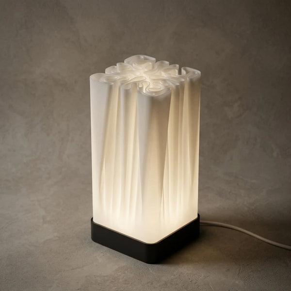 3CHIC The Fold lamp glowing softly, tall white pleated shade on a slim black base, USB powered LED, made in Dubai