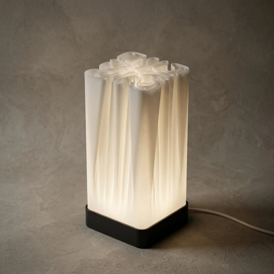 3CHIC The Fold lamp glowing softly, tall white pleated shade on a slim black base, USB powered LED, made in Dubai