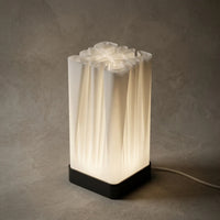 3CHIC The Fold lamp glowing softly, tall white pleated shade on a slim black base, USB powered LED, made in Dubai